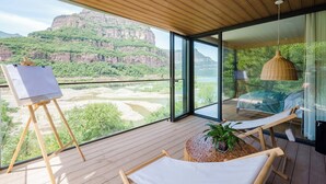 Una habitación moderna con un amplio ventanal con vistas a un cañón, una hamaca y un caballete.