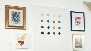 Una habitación con una mesa de comedor, una silla y una pared decorada con varias obras de arte enmarcadas.