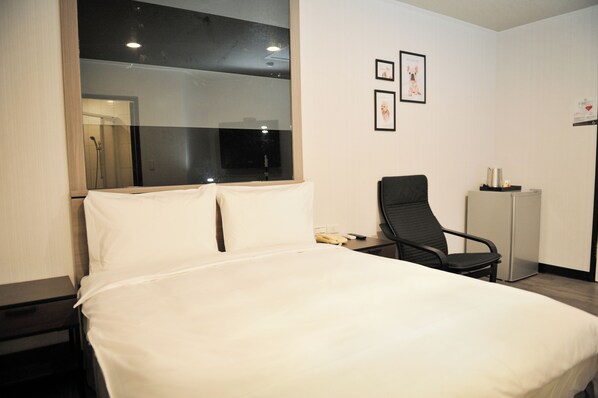 Ein Hotelzimmer mit einem großen Bett, einem Sessel, einem Schreibtisch und einem Spiegel.