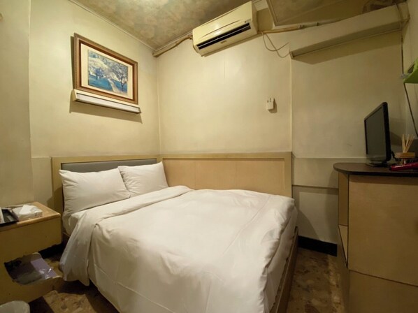 A hotel room with a bed, a nightstand, a desk with a computer, an air conditioner, and a framed picture on the wall. - HUANG KAI (Taichung)