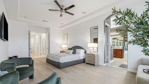 Ein modernes Schlafzimmer mit Bett, Nachttischen, Deckenventilator und einem großen Spiegel.