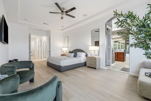 A modern bedroom with a bed, bedside tables, a ceiling fan, and a large mirror. - 4BR Indio Desert Escape • Stylish Stay • Mountain Views (Indio)