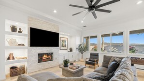 A modern living room with a fireplace, a flat-screen TV, and a large window with a view of the desert. - 4BR Indio Desert Escape • Stylish Stay • Mountain Views (Indio)