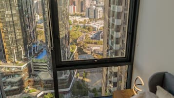 Un appartement situé dans un immeuble de grande hauteur, doté d’une grande fenêtre offrant une vue sur la ville.