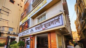 A jewellery store with a sign in English and another language, located on a street with buildings on either side. - EENNRA ARAMMBAGH (Arambag)