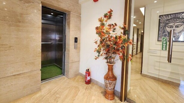 Un ascenseur, un extincteur et un vase décoratif orné de feuillage.