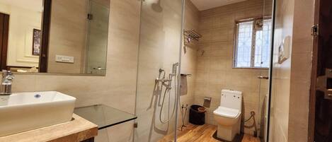 Un baño moderno con cabina de ducha de vidrio, un lavabo blanco y un inodoro.