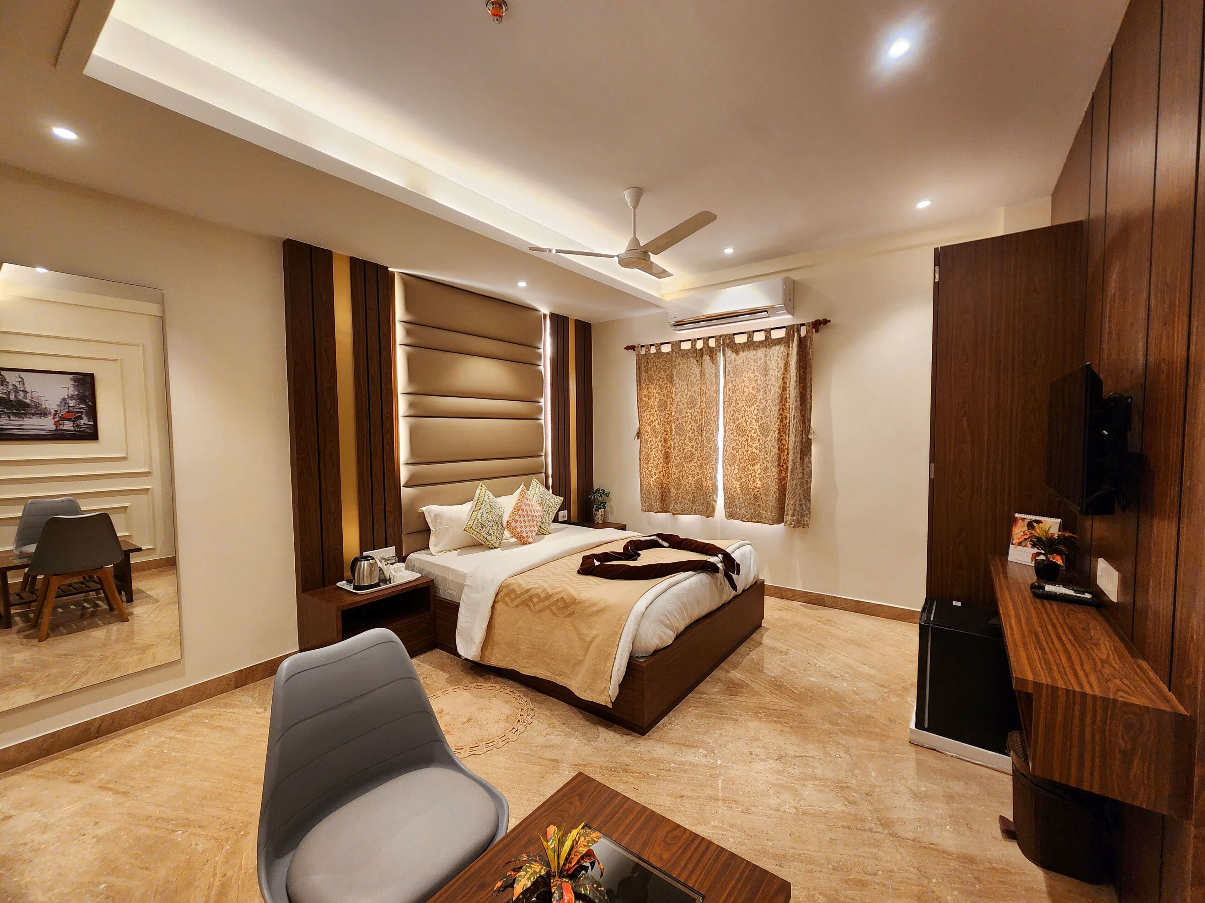 Una habitación de hotel moderna con cama, escritorio, silla, televisor y ventilador de techo.
