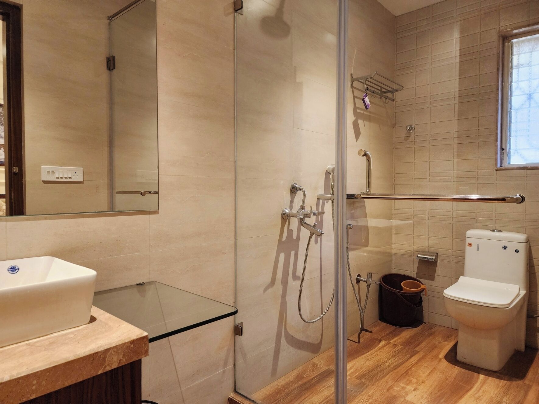 Un baño moderno con cabina de ducha de vidrio, un lavabo blanco y un inodoro.