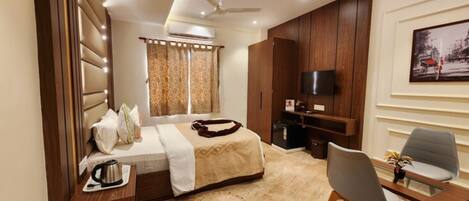 A modern hotel room with a bed, a desk, a chair, a TV, and a painting on the wall.