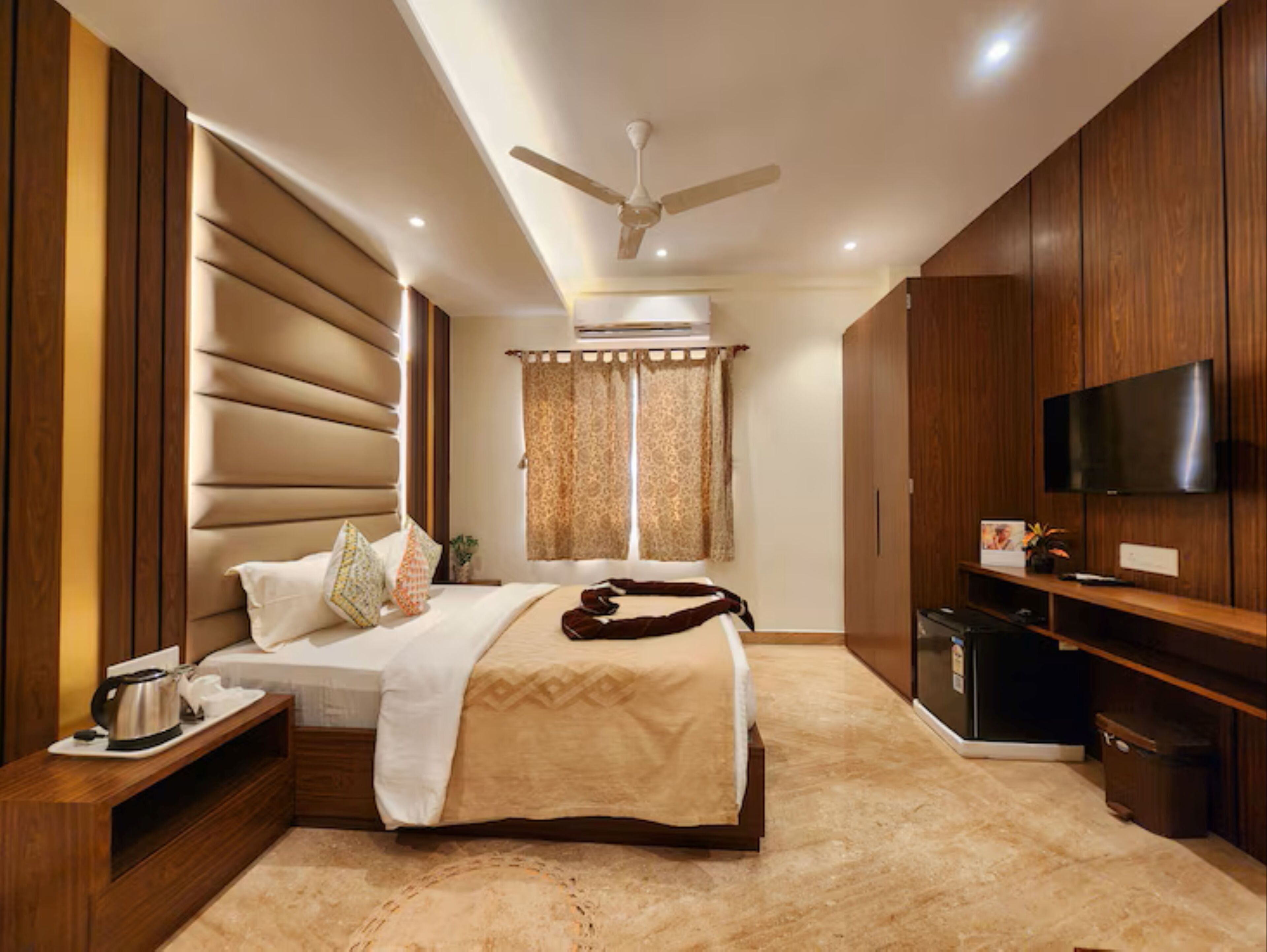 Ein modernes Schlafzimmer mit Bett, Nachttisch, Fernseher und Deckenventilator.