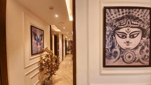 A hallway with framed artwork, a potted plant, and a marble floor. - EENNRA ARAMMBAGH (Arambag)
