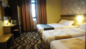 Habitación de hotel con dos camas, un escritorio, un televisor y una alfombra estampada.
