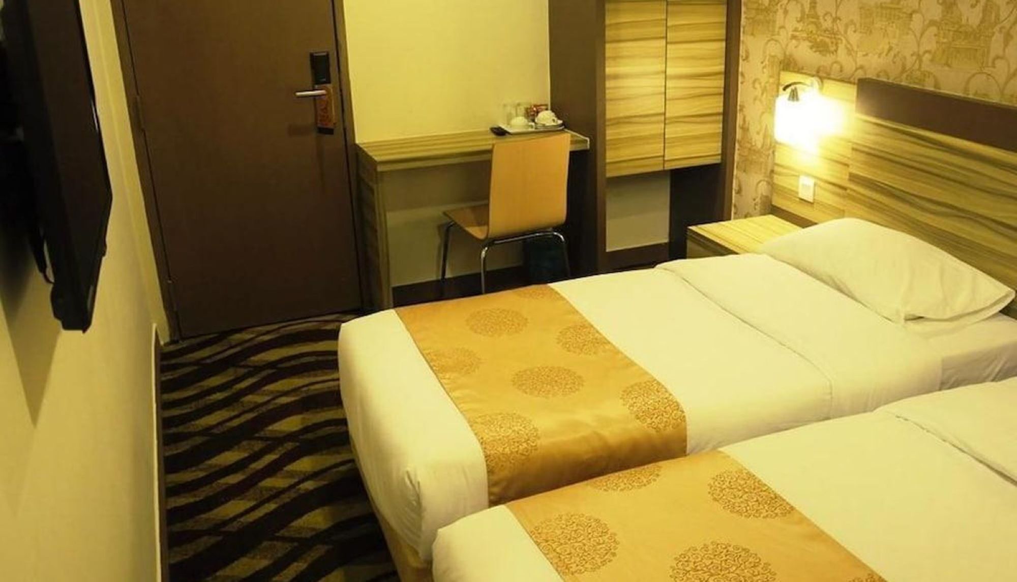 Habitación de hotel con dos camas, un escritorio y una silla.