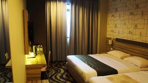 A hotel room with two beds, a desk with a chair, a TV, and a window with curtains. - Victory City Hotel Crystal Bay (Johor Bahru)