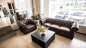 A modern living room with a brown leather sofa, a matching armchair, and a coffee table. - Victory City Hotel Crystal Bay (Johor Bahru)