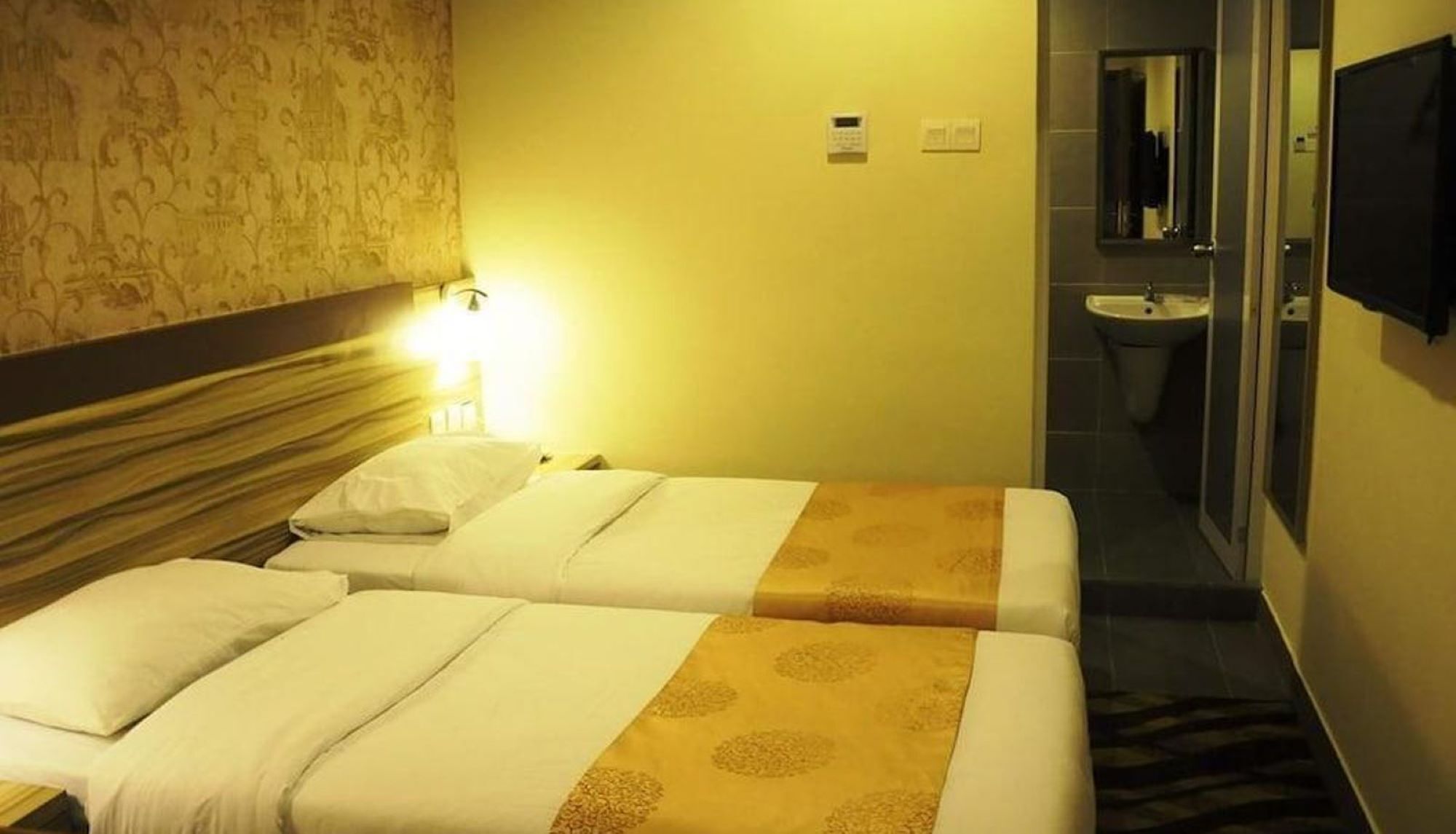 A hotel room with two beds, a bathroom with a sink, and a mirror.