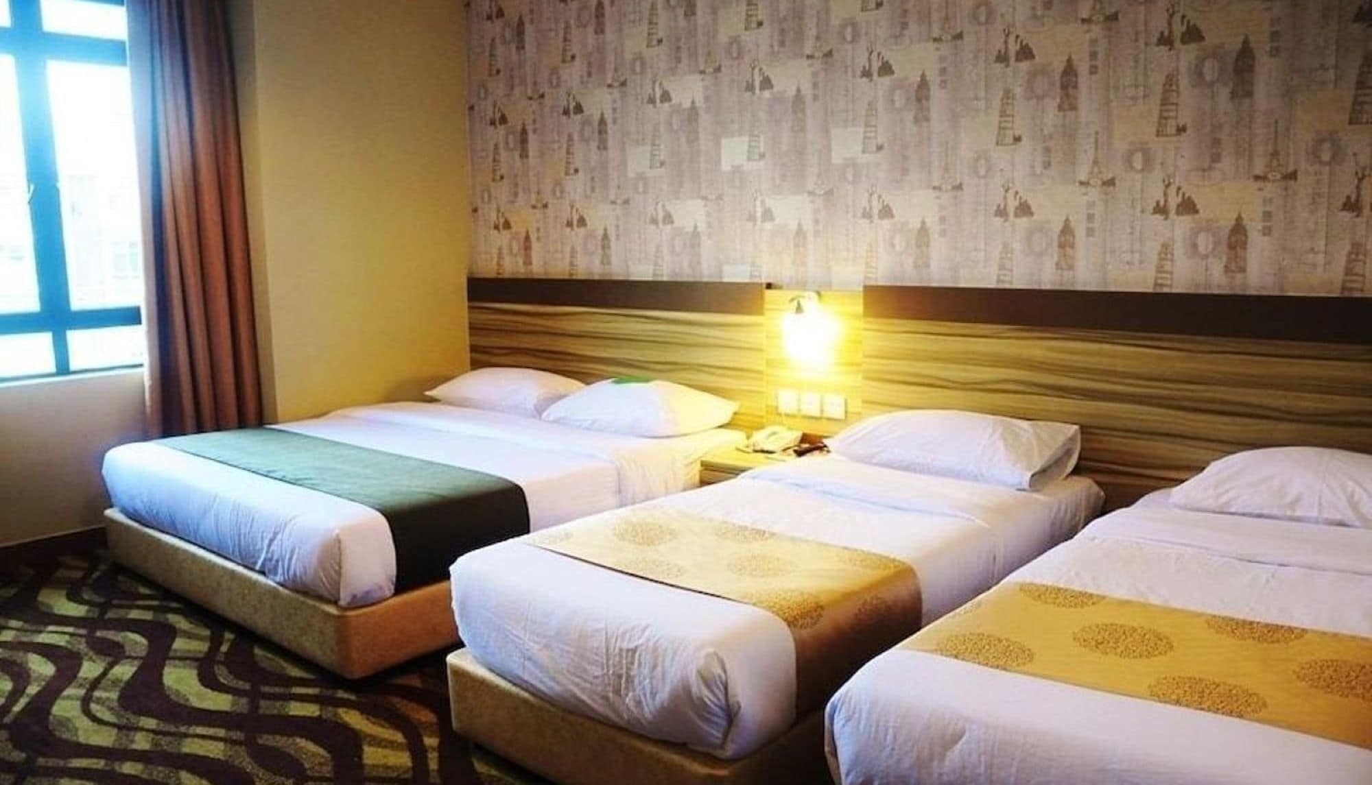 Ein Hotelzimmer mit zwei Betten, einem Nachttisch mit Lampe und einer Wand mit Muster.
