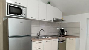 A modern kitchen with a built-in microwave, stainless steel refrigerator, and a coffee maker on the countertop. - Apartments Tomislav (Vrsi)