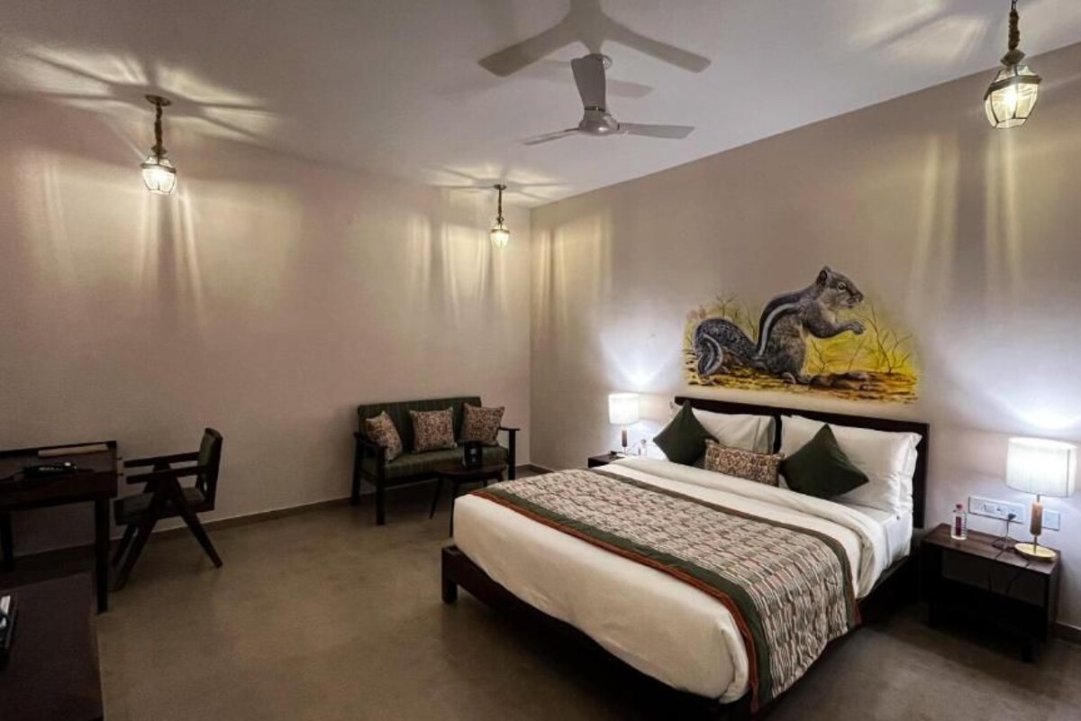 Ein Schlafzimmer mit einem Bett, einem Schreibtisch, einem Stuhl, einem Nachttisch und einem an der Wand hängenden Kunstwerk.
