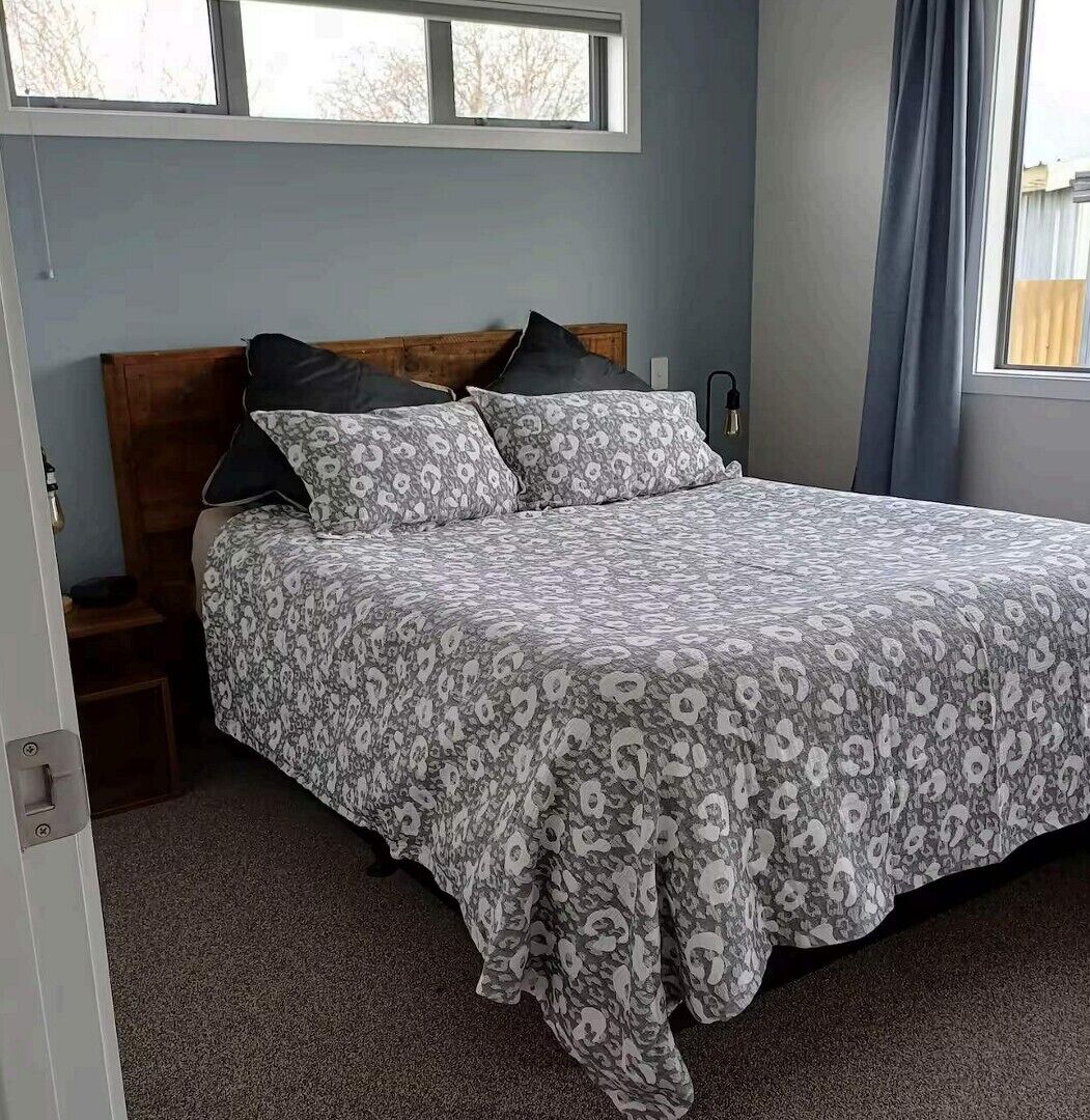 A bedroom with a bed, a nightstand, a window, and a curtain.