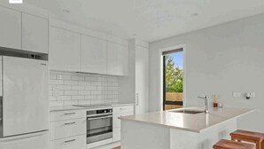 Une cuisine moderne avec des meubles blancs, un îlot central et des tabourets en bois.