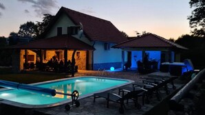Une maison avec une piscine, un espace extérieur aménagé pour s’asseoir et une terrasse couverte.