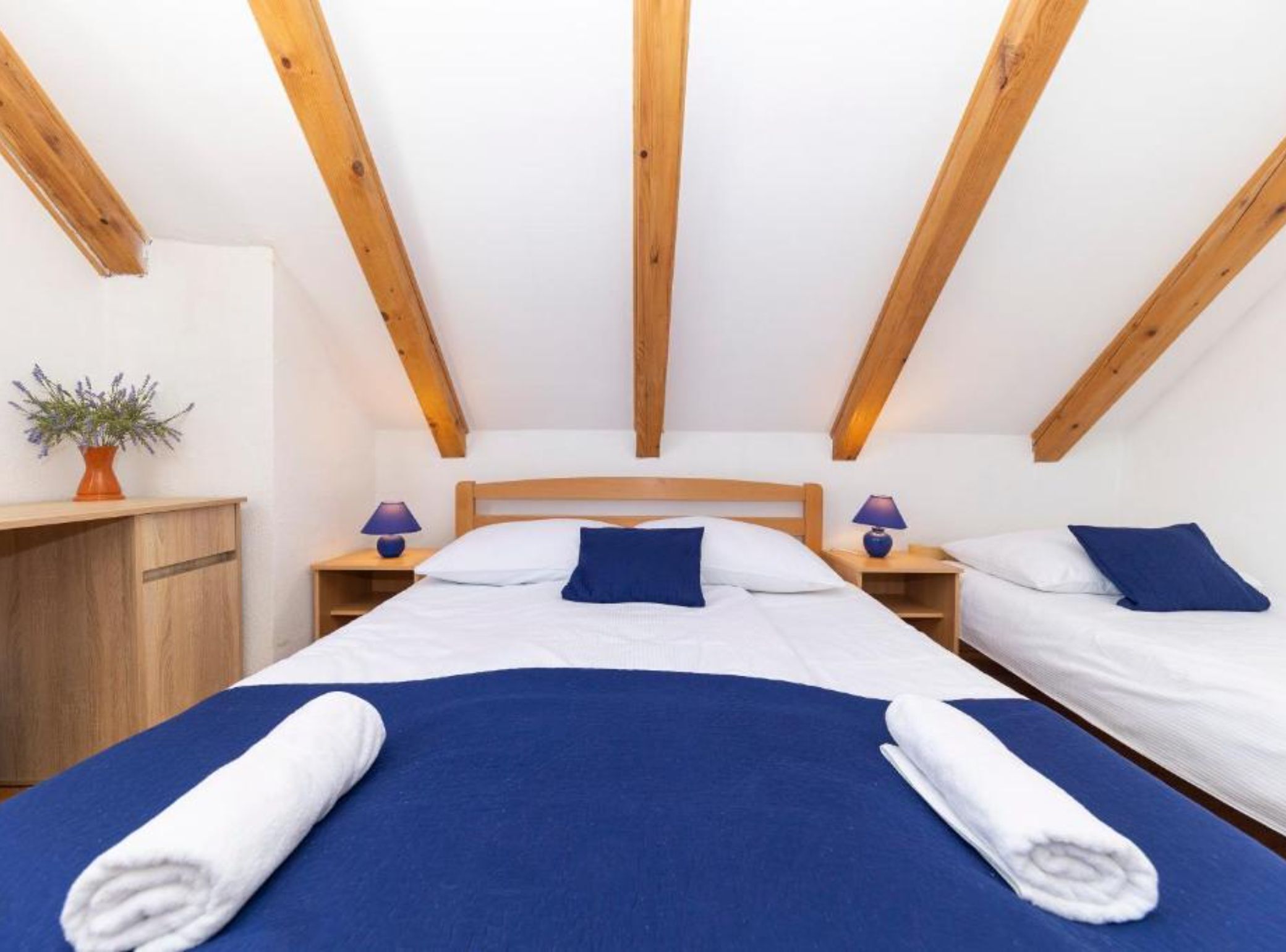 A bedroom with a large bed, two bedside tables, and a wooden ceiling.