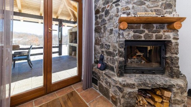 Une cheminée en pierre avec une étagère à bois et un banc à l’extérieur.