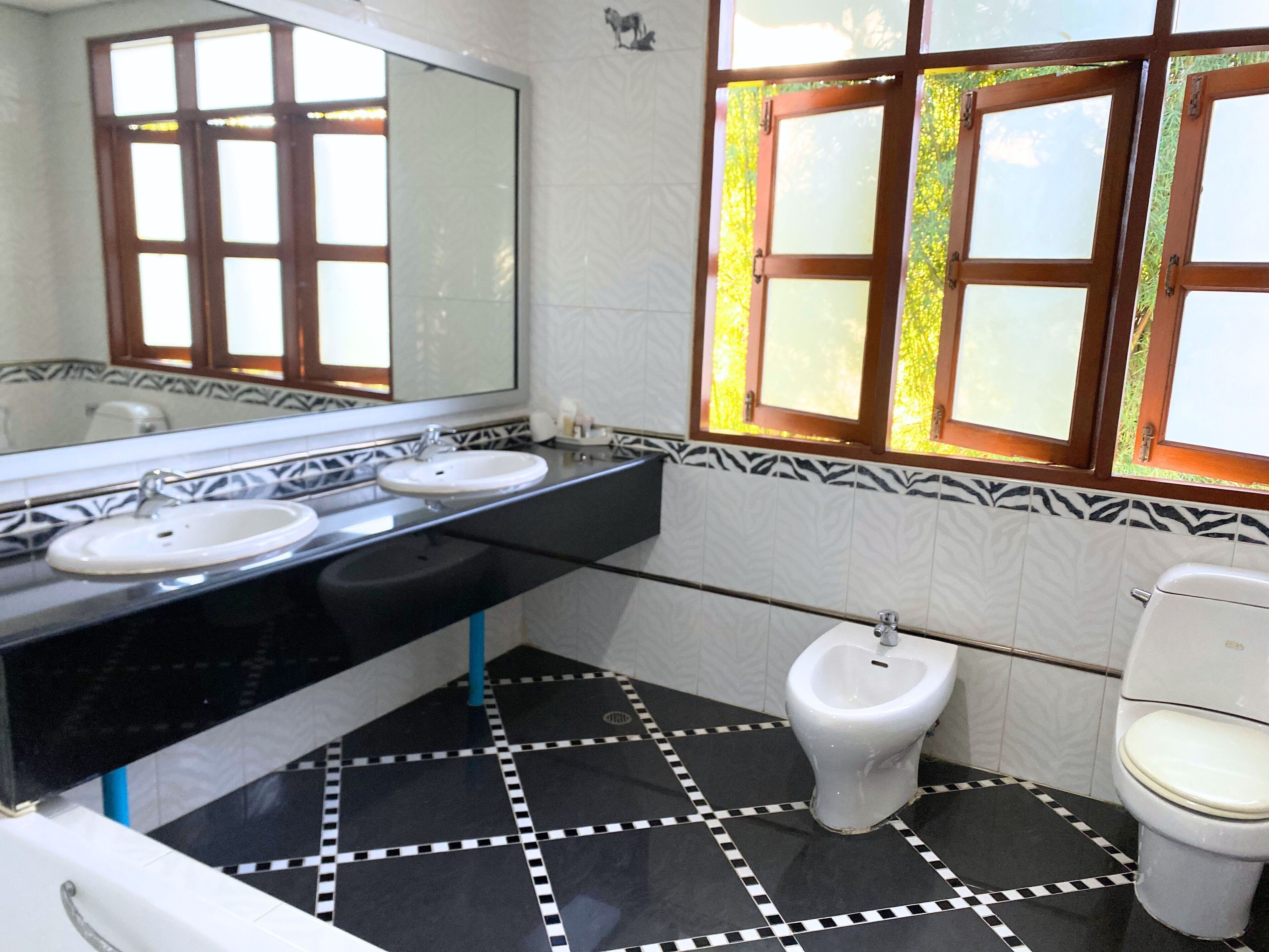 Een badkamer met twee wasbakken, een toilet en een hygiëneschuimer.