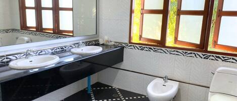 A bathroom with two sinks, a bidet, and a toilet.