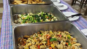 Een buffettafel met diverse gerechten, waaronder friture, salade en roerbakgerecht.