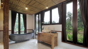 A bathroom with a large bathtub, wooden vanity, and large windows with curtains. - The Tirta Sari Villas (Tegallalang)