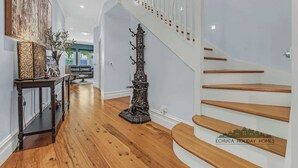 Un pasillo amplio con escalera de madera y una escultura decorativa de metal.