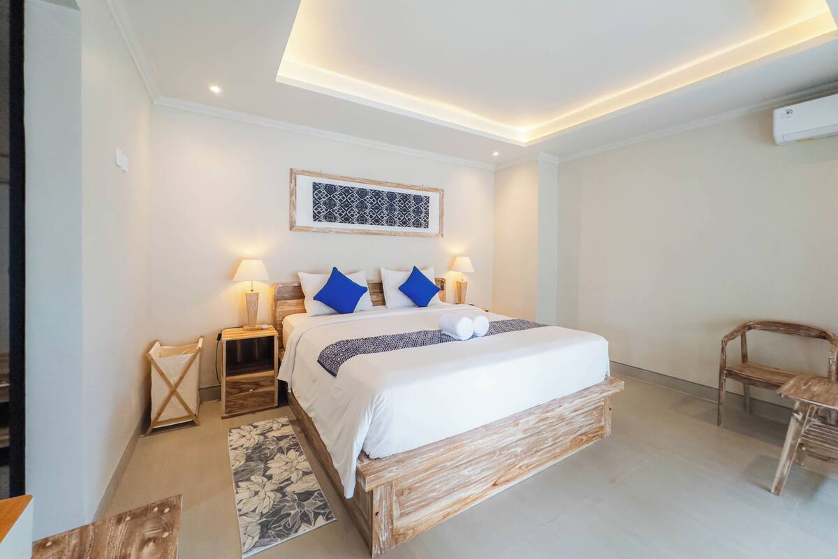 Un dormitorio moderno con una cama de madera, paredes blancas y una lámpara en el techo.