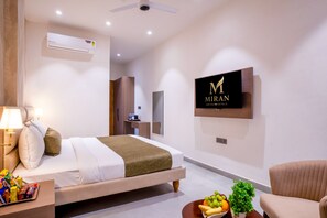 Una habitación de hotel moderna con una cama, mesita de noche, lámpara, televisor y un frutero.