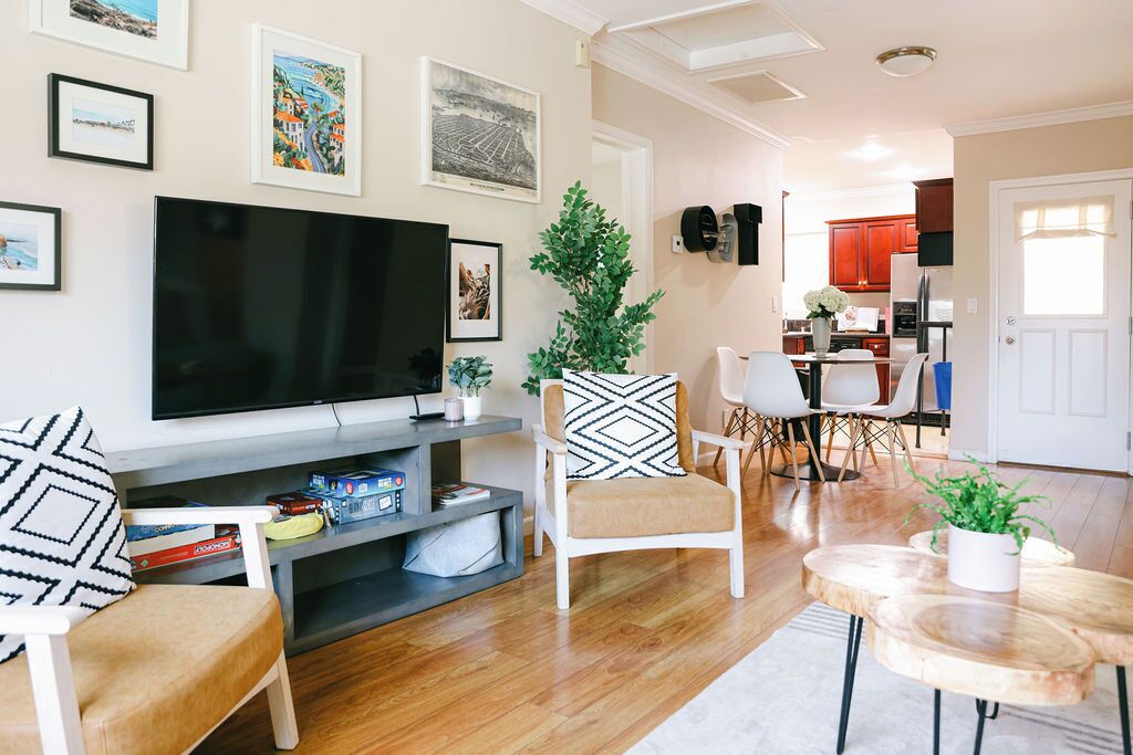 A living room with a flat-screen TV, a coffee table, a sofa, and a dining area with chairs.