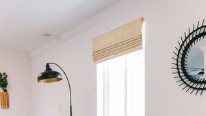 Ein modernes Wohnzimmer mit einem grauen Sofa, einer grünen Schale mit Snacks, einer schwarzen Lampe und einem gemusterten Teppich.