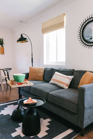 A modern living room with a grey sofa, a green bowl of snacks, a black lamp, and a patterned rug. - Side-by-Side Homes - Near Zoo & Gaslamp (San Diego)