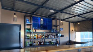 A bar area with a wooden counter, shelves of various bottles, and two modern chairs. - Amoria Boutique Hotel (Tigoni)