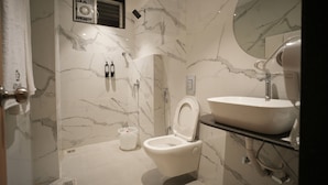 Une salle de bain moderne avec un mur en marbre, des toilettes, un lavabo et un miroir.
