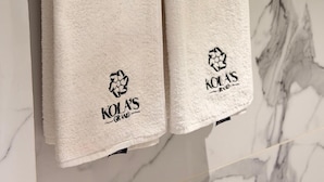 Deux serviettes blanches sont suspendues à un porte-serviettes en métal, avec un mur de marbre en arrière-plan.