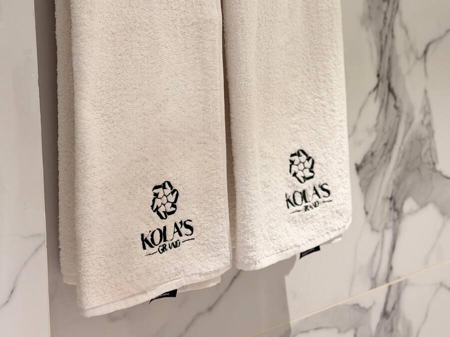 Two white towels hanging on a metal towel rack with a marble wall in the background.