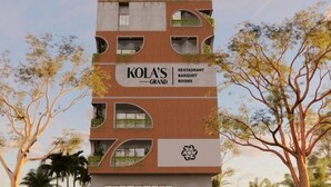 Un immeuble à plusieurs étages sur lequel on peut lire l’inscription « KOLA’S GRAND Restaurant, salles de banquet ».