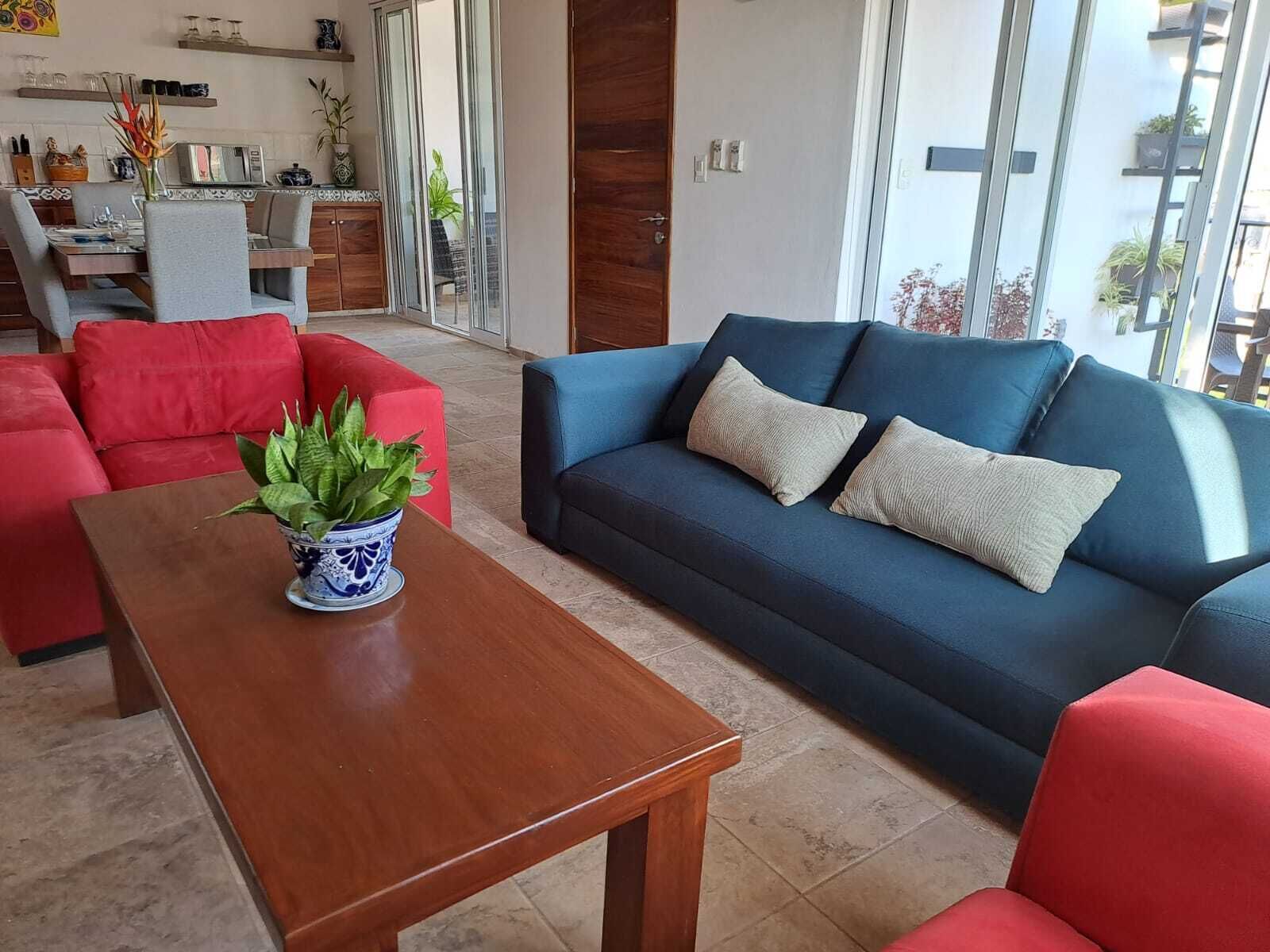 Ein modernes Wohnzimmer mit einem blauen Sofa, roten Sessel und einem Holztisch.