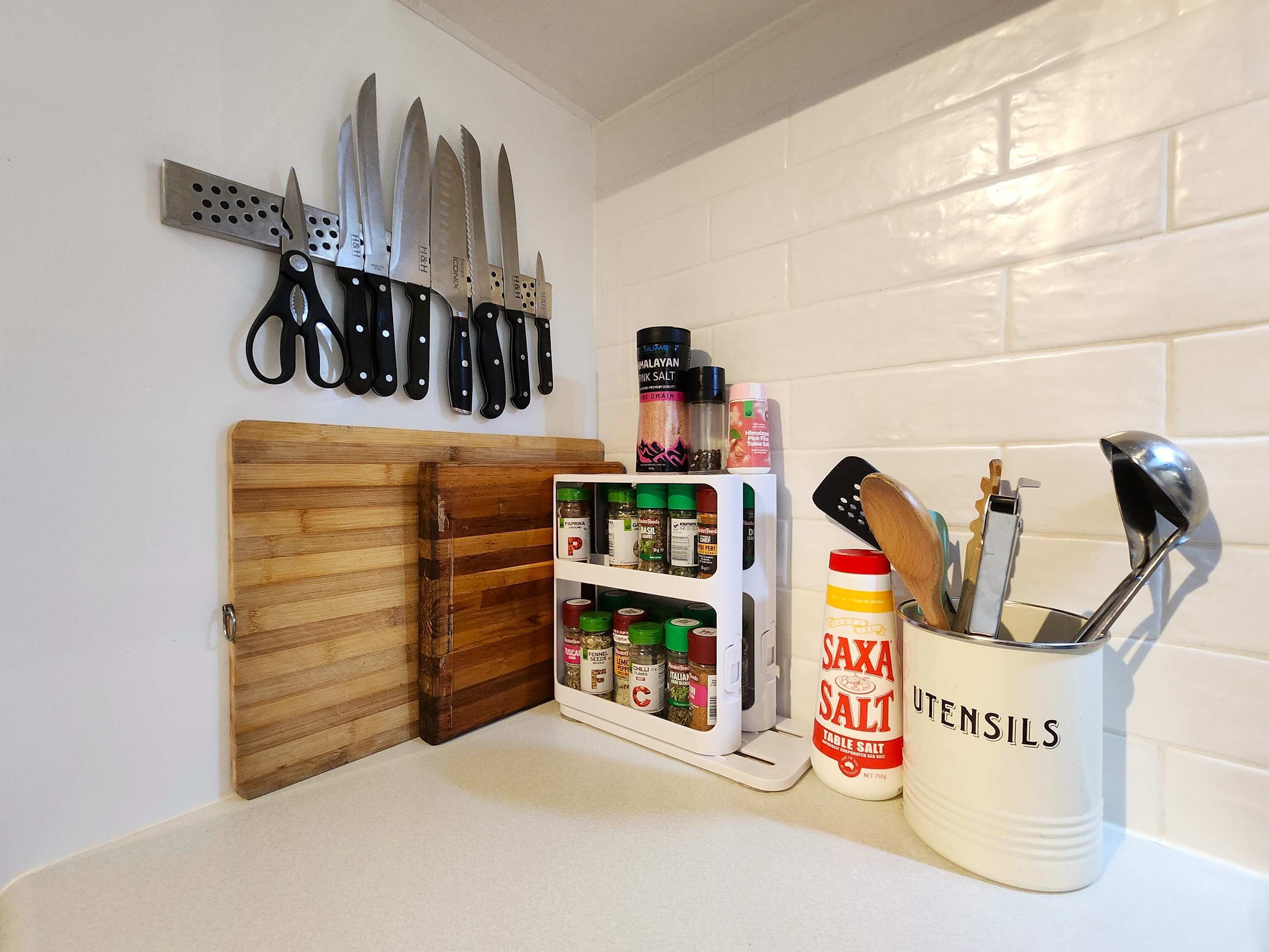 Uma bancada de cozinha com um porta-facas, um porta-temperos e um suporte para utensílios.