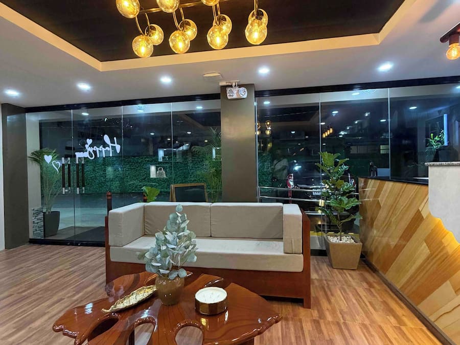 Un vestíbulo moderno con piso de madera, un área de estar central con un sofá, una mesa de centro de madera y una planta decorativa.
