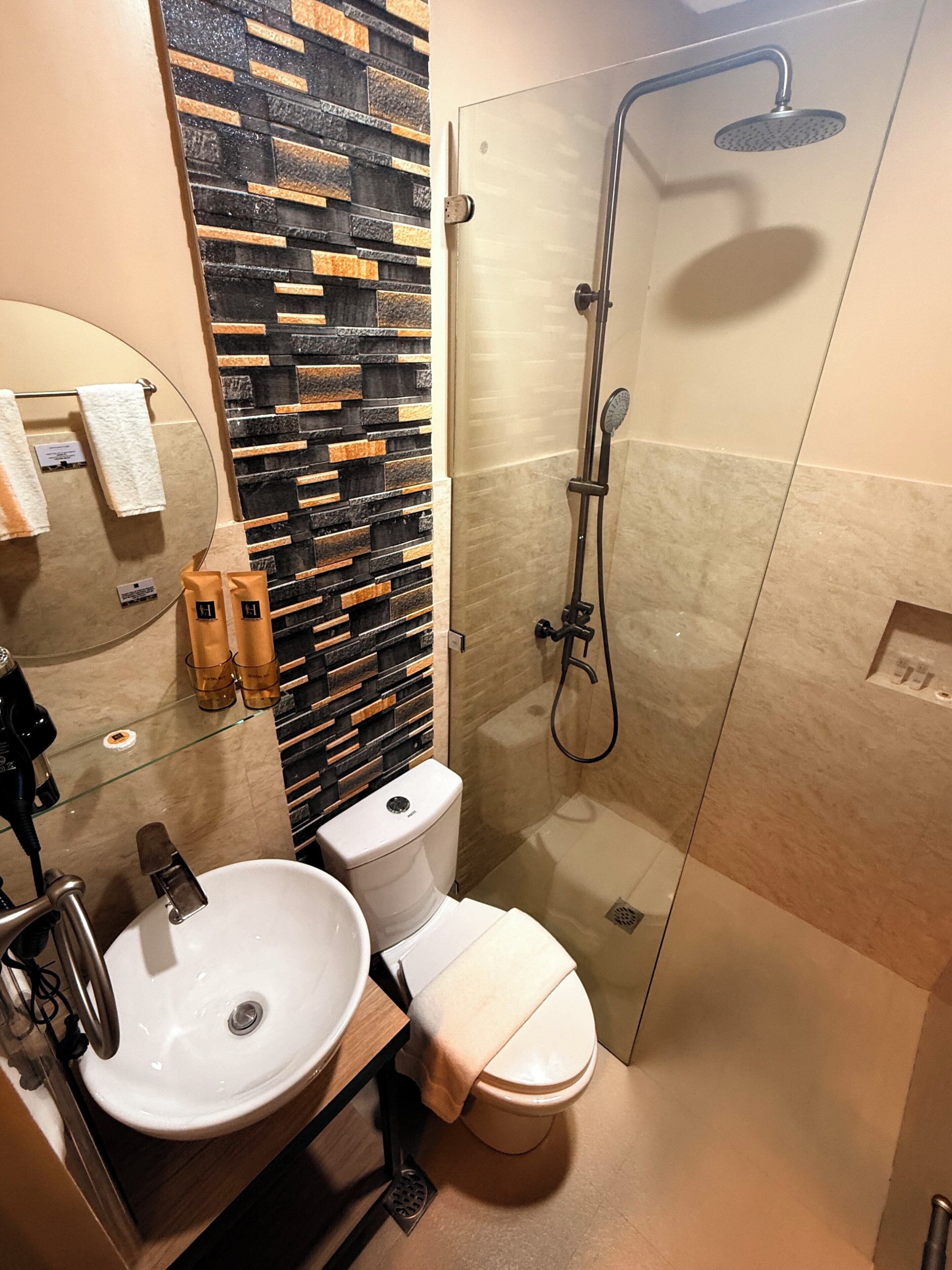 A modern bathroom with a glass-enclosed shower, a white sink, and a toilet.