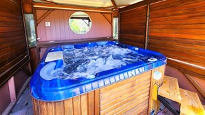 Un jacuzzi en una cabaña de madera con tragaluces y una ventana pequeña.