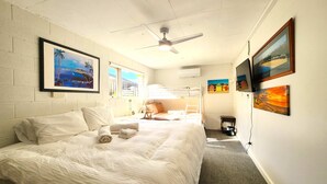 Una habitación de hotel con una cama grande, ventilador de techo y obras de arte en las paredes.